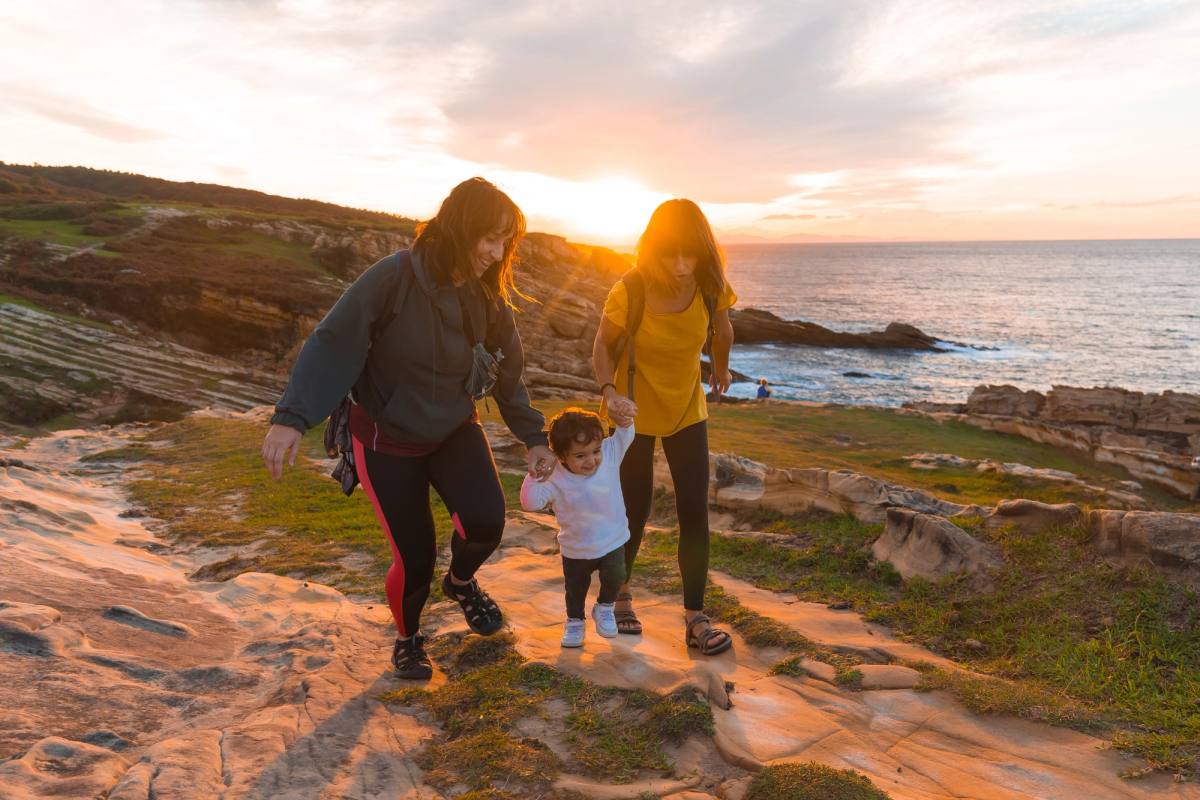 A family walking a rocky shore at sunset