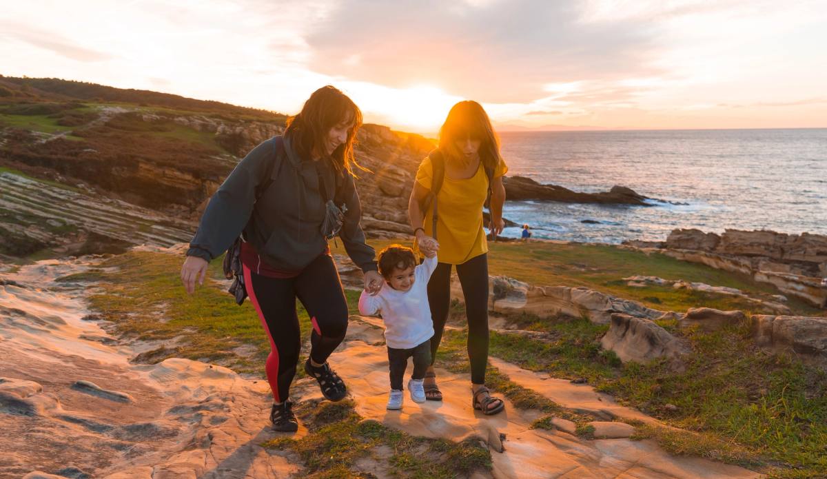 A family walking a rocky shore at sunset