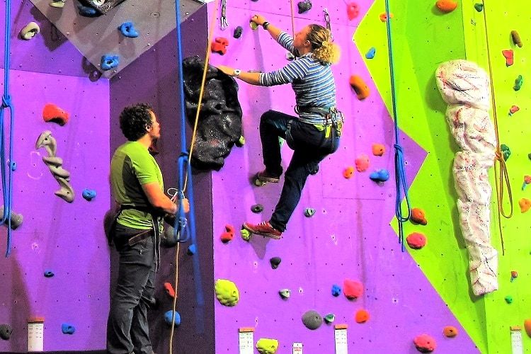 Two climbers working brightly coloured routes on an indoor climbing wall