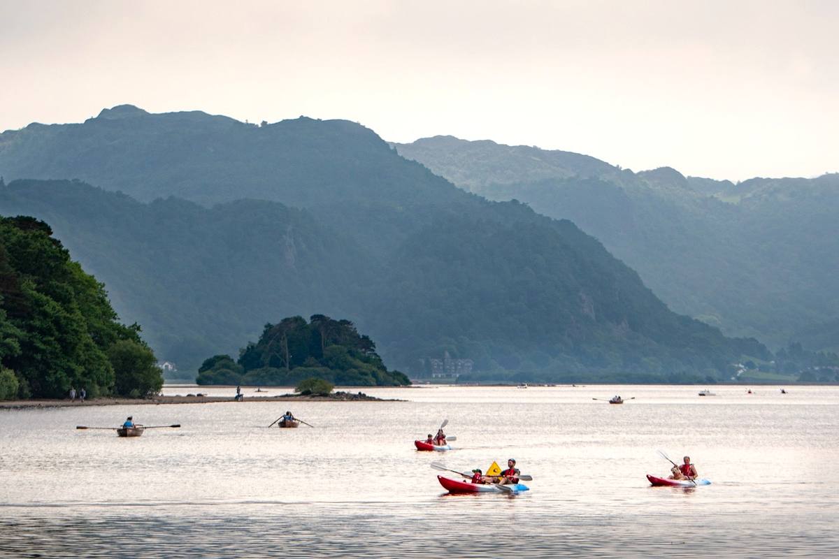 Kayakers paddling past one of the wooded islands on Derwentwater