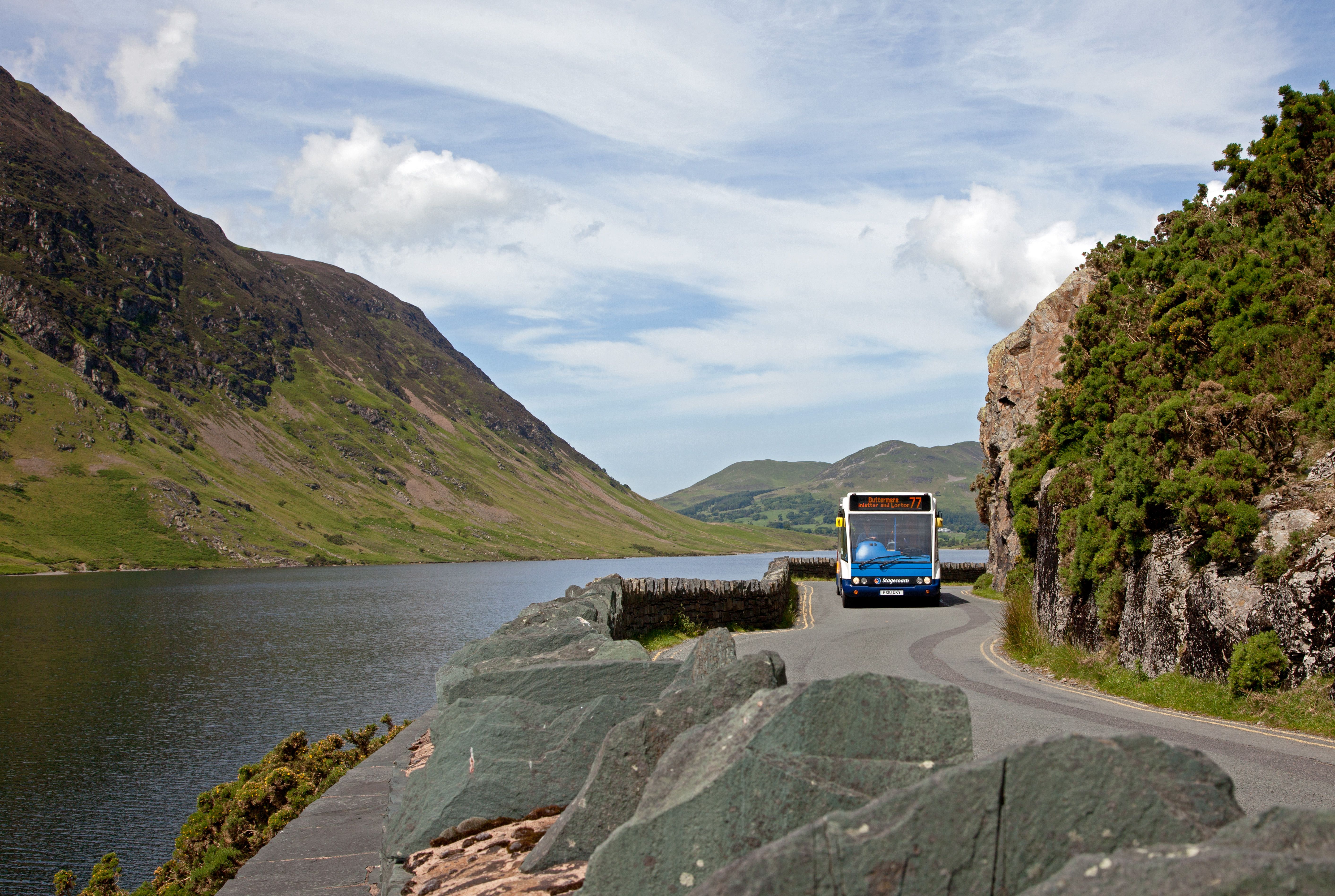 Bus coming around the windy narrow road next to crummock water lake 