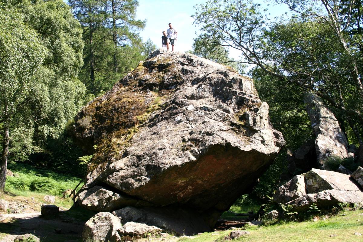 Two people standing on top of the Bowder Stone showing the scale of it