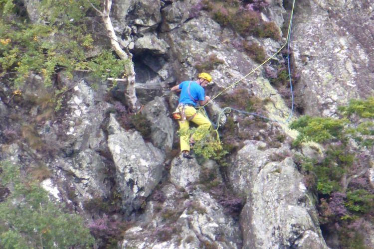 A climber in a helmet working up a steep rock face