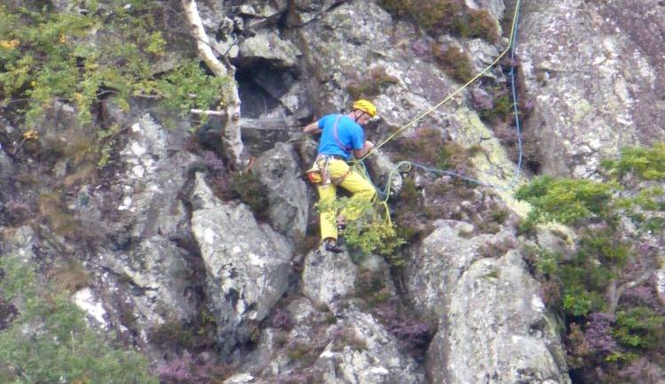 A climber in a helmet working up a steep rock face