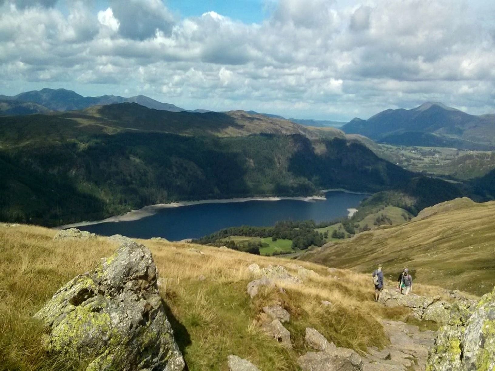 Walkers on a rocky path high above Thirlmere with the fells beyond