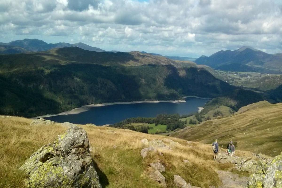 Walkers on a rocky path high above Thirlmere with the fells beyond