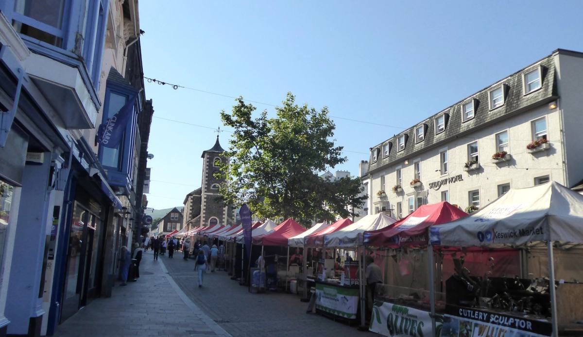 Covered market stalls set out down the middle of Keswick main street on market day