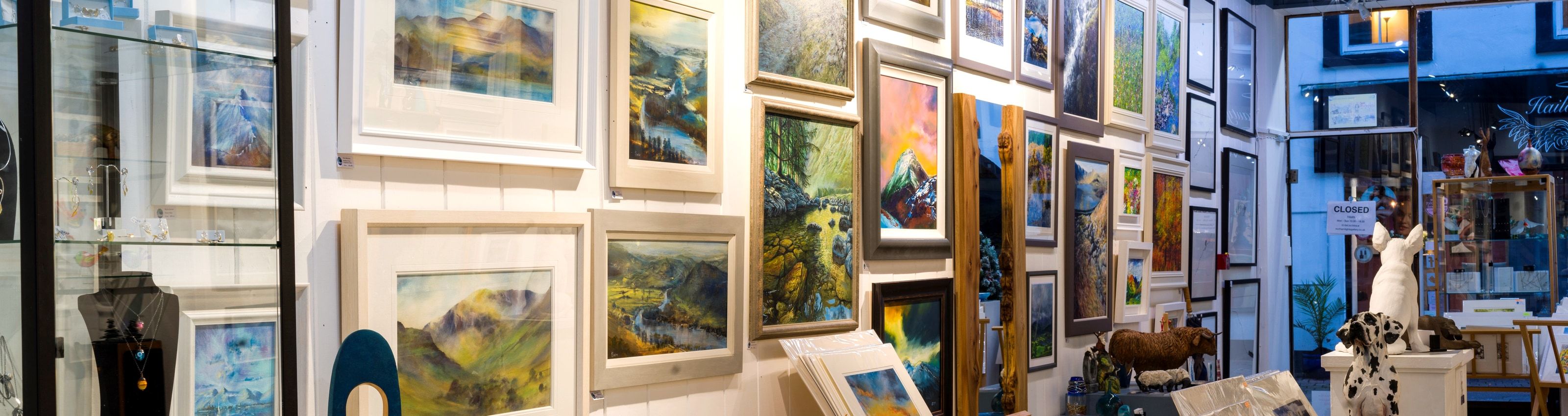 Framed landscape paintings hung close together on a gallery wall