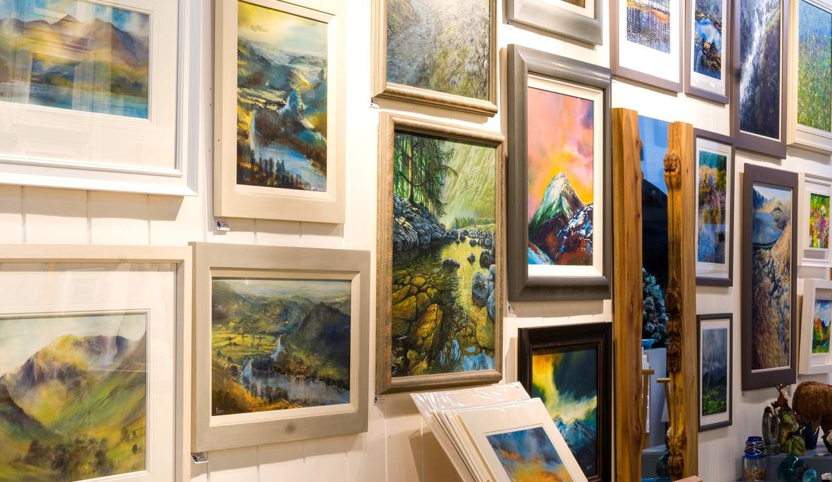 Framed landscape paintings hung close together on a gallery wall