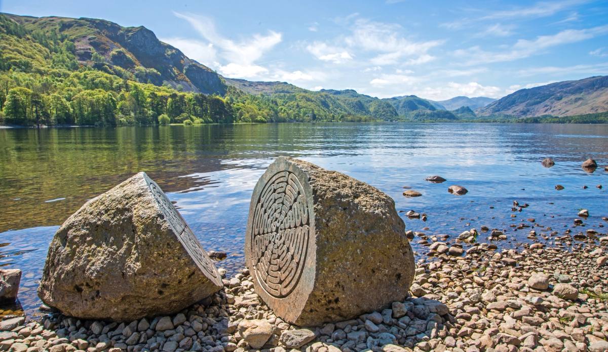 A carved spiral stone sculpture set on the shingle at the edge of Derwentwater