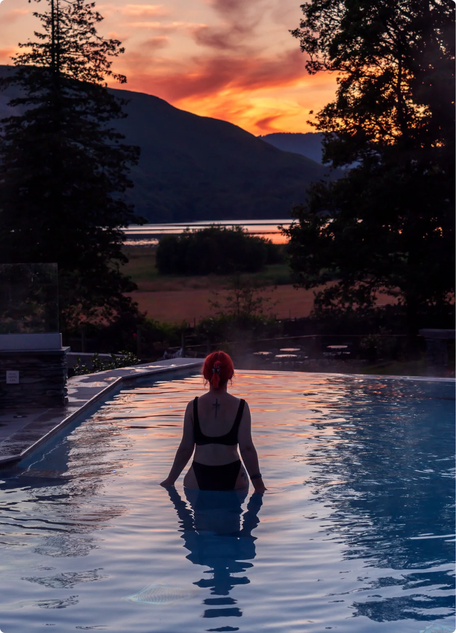 Woman in swimming pool overlooking Keswick scenery at sunset