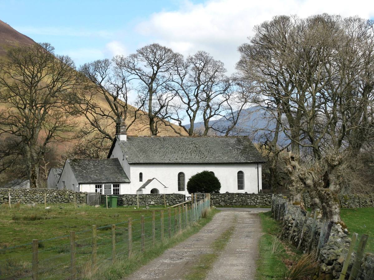 A farm track running between bare trees to the little whitewashed Newlands church