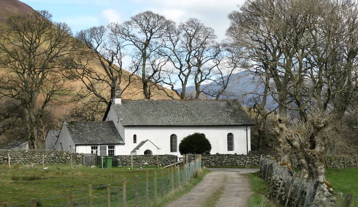 A farm track running between bare trees to the little whitewashed Newlands church