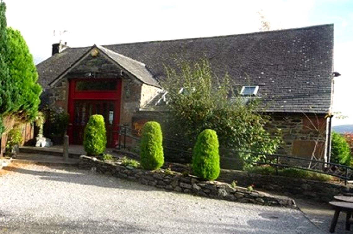 The red door and slate frontage of the gallery at Thornthwaite behind clipped hedges