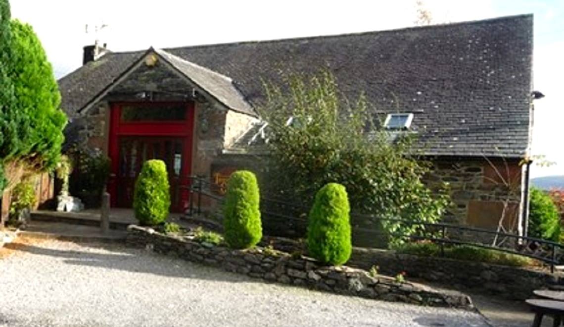 The red door and slate frontage of the gallery at Thornthwaite behind clipped hedges