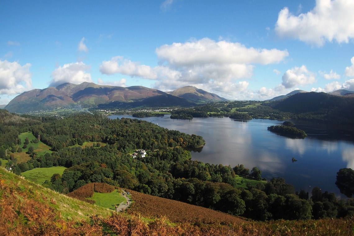 Derwentwater and its wooded shore seen from the ridge with cloud shadow on the fells