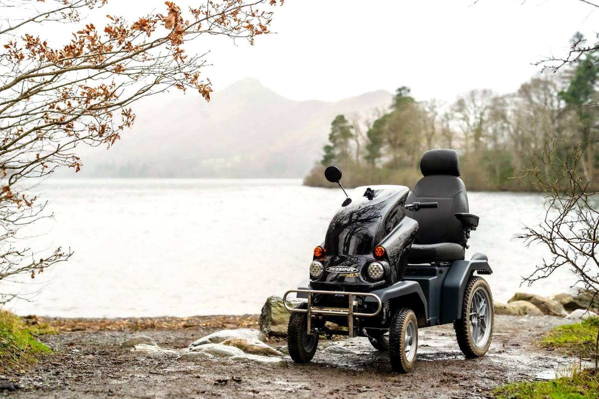 An all-terrain mobility scooter parked on the shingle at the edge of the lake