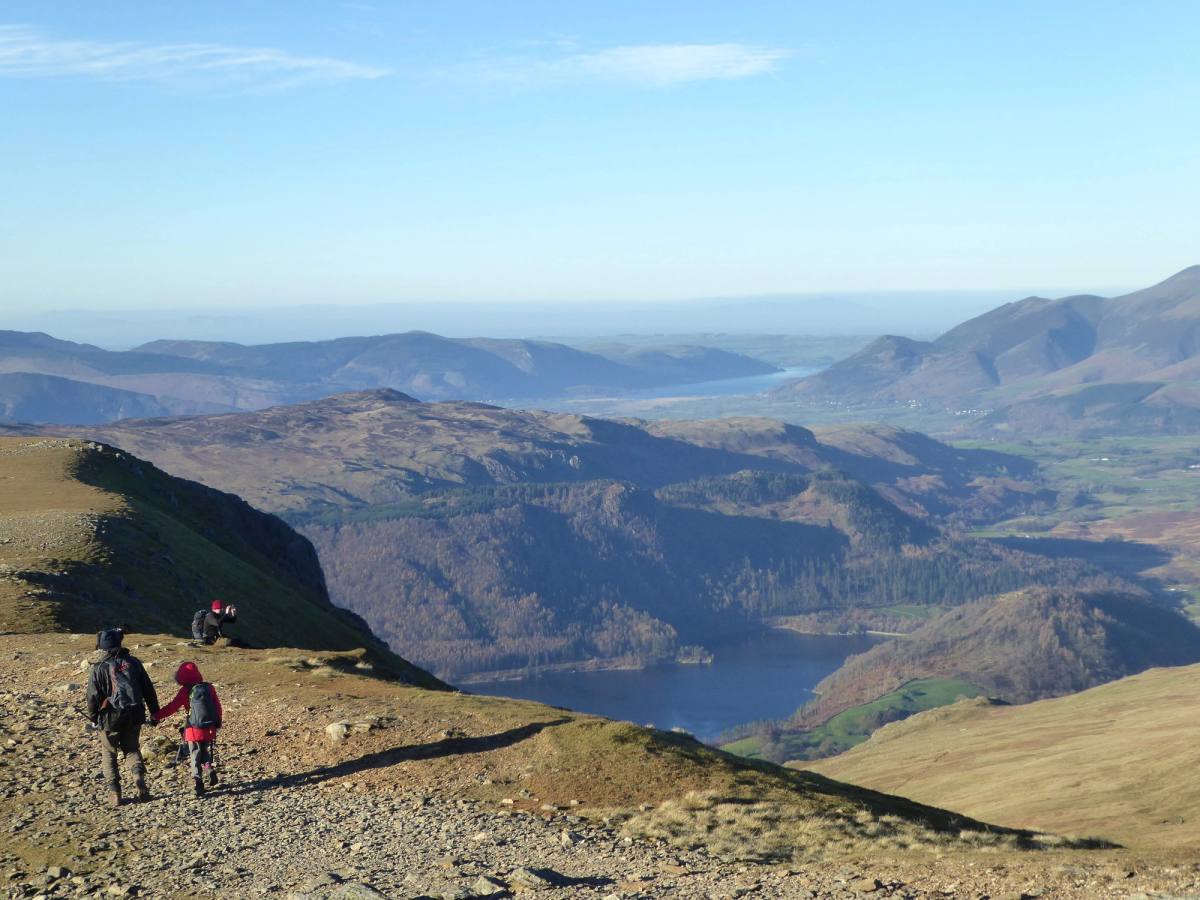 Two walkers on a stony path high above Thirlmere with the lake far below