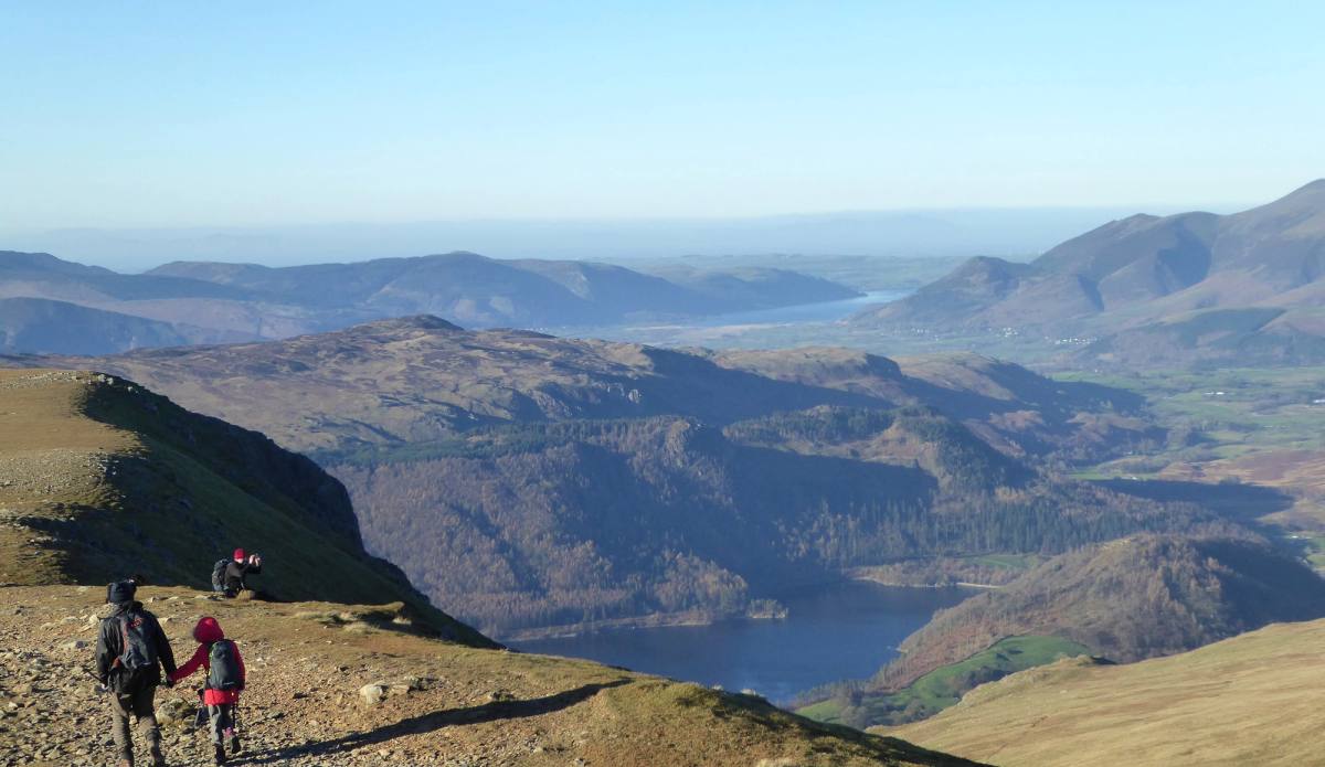 Two walkers on a stony path high above Thirlmere with the lake far below