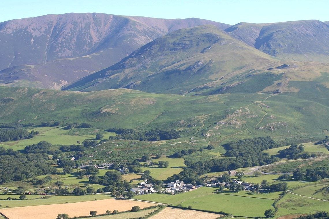 Green fields and farms of the Lorton valley with the high fells rising beyond