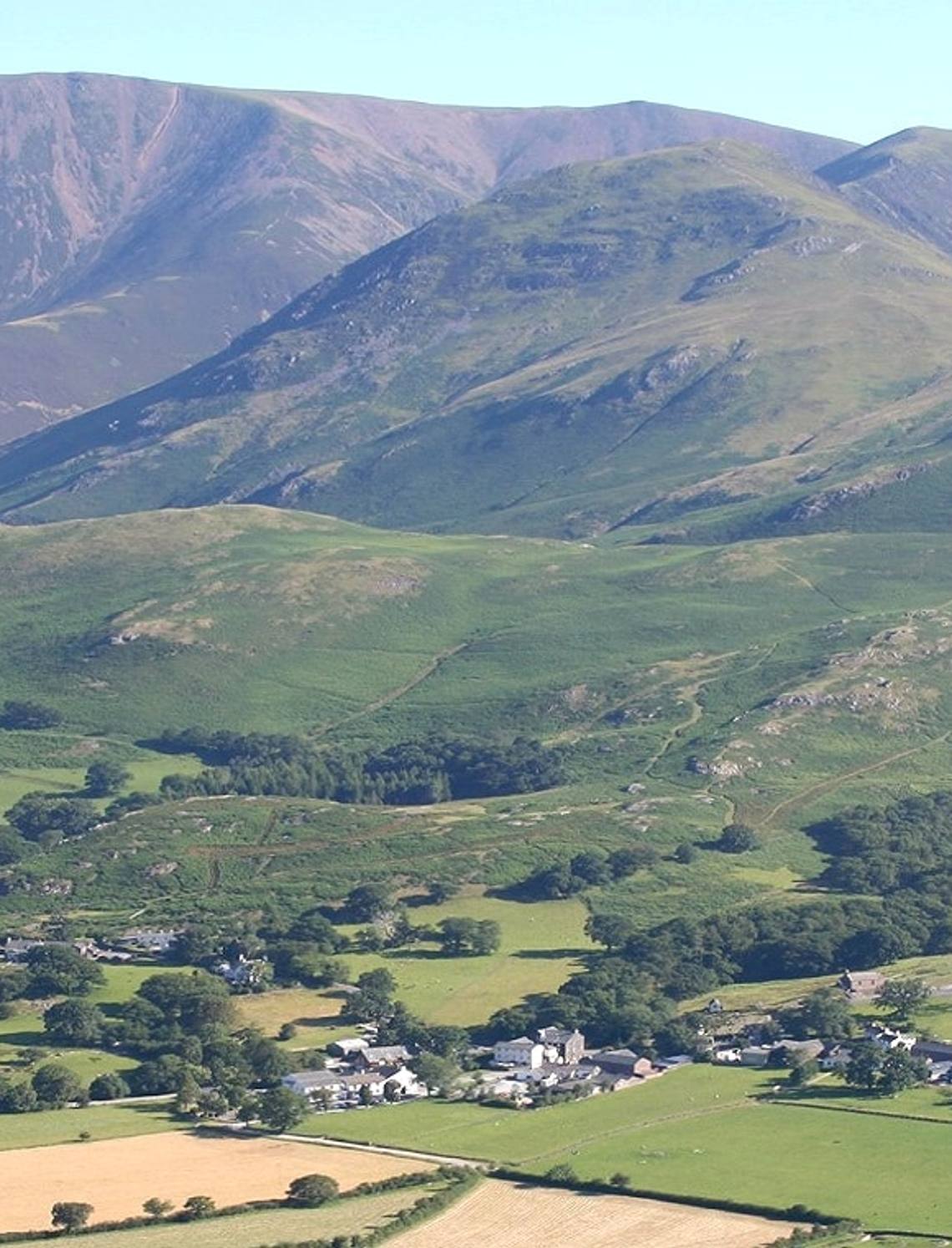 Green fields and farms of the Lorton valley with the high fells rising beyond