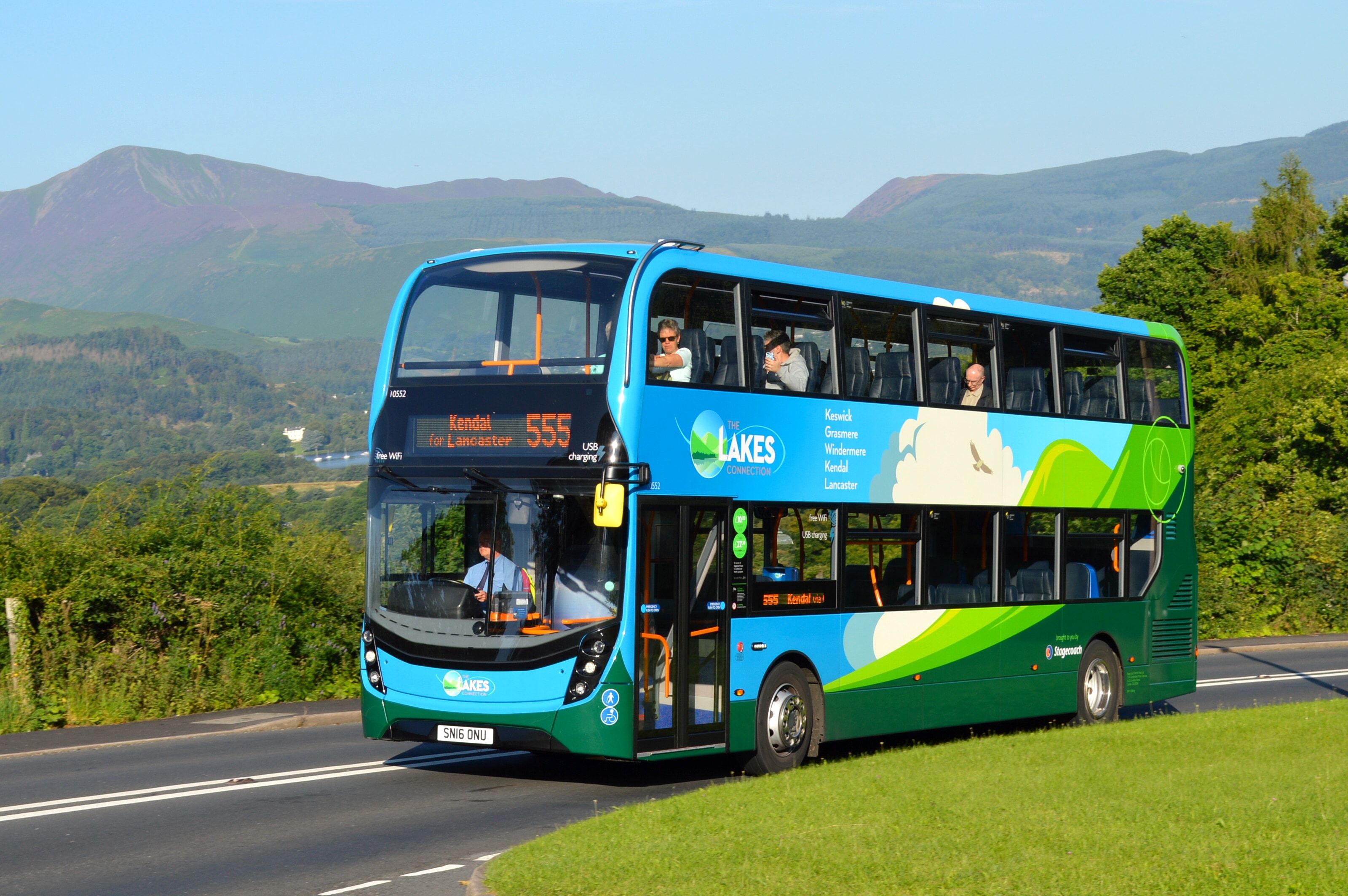 A Stagecoach 555 double-decker bus on the valley road with the fells behind