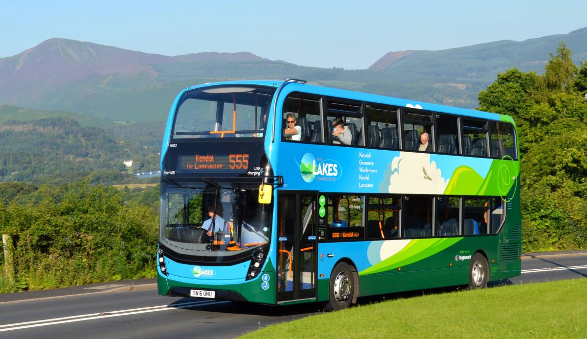 A Stagecoach 555 double-decker bus on the valley road with the fells behind