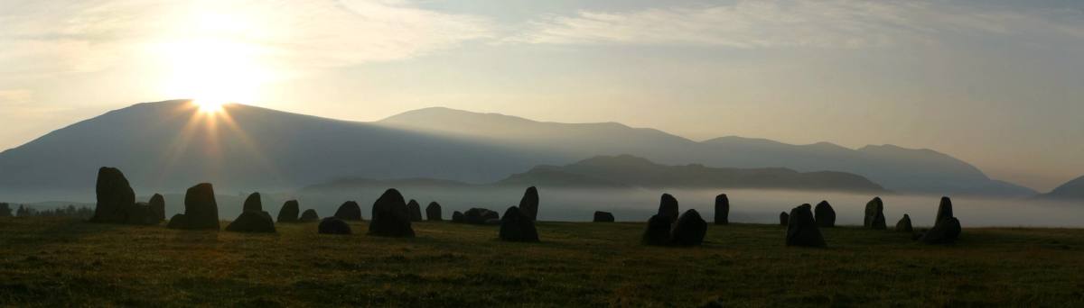 The standing stones of Castlerigg at dawn with mist lying across the fells behind