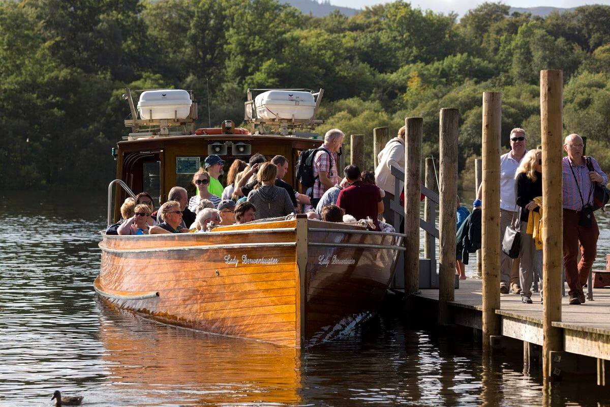 Passengers stepping aboard a wooden launch at the Derwentwater landing stages