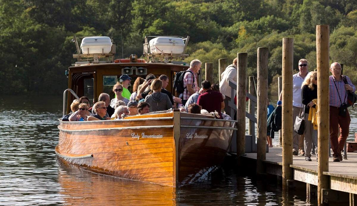 Passengers stepping aboard a wooden launch at the Derwentwater landing stages