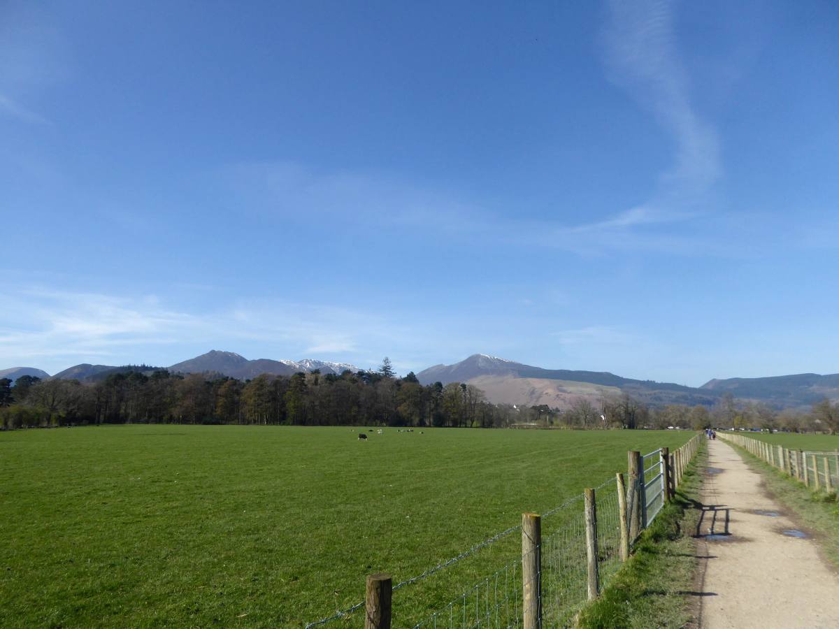 A footpath running across open fields towards the bulk of Skiddaw