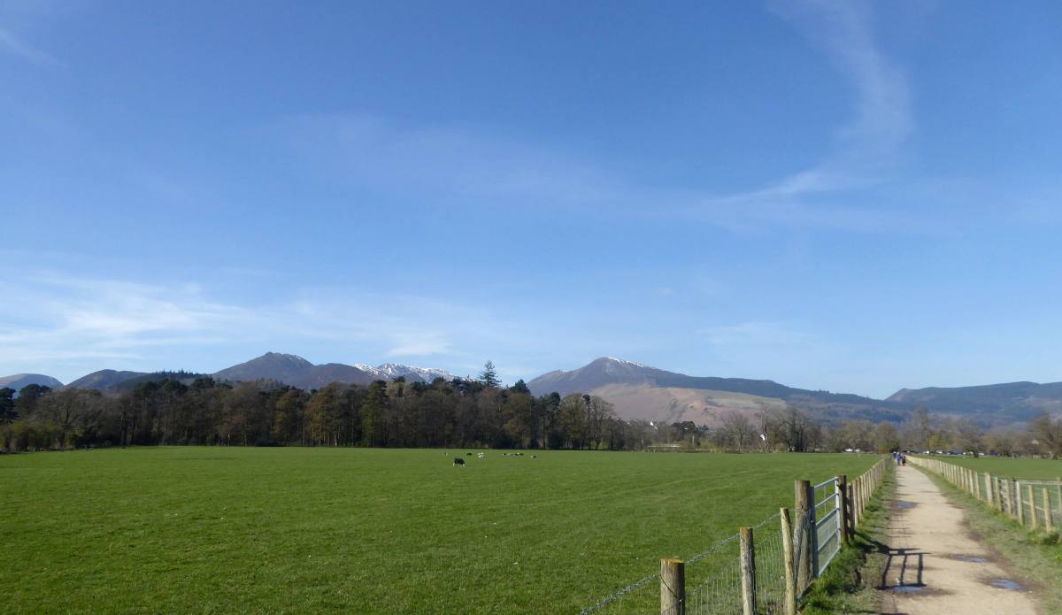 A footpath running across open fields towards the bulk of Skiddaw
