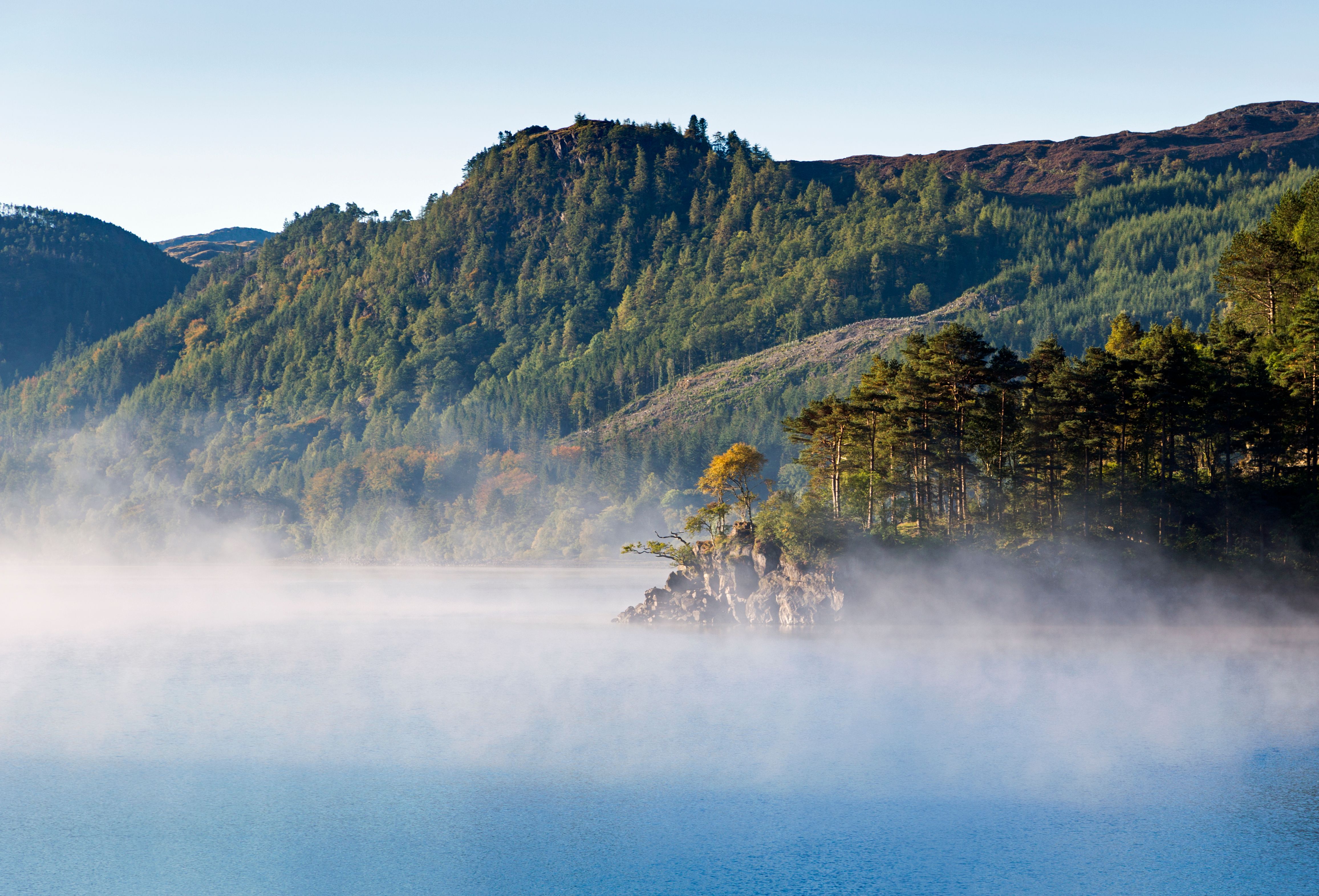misty clouds on top of water with woodland fells