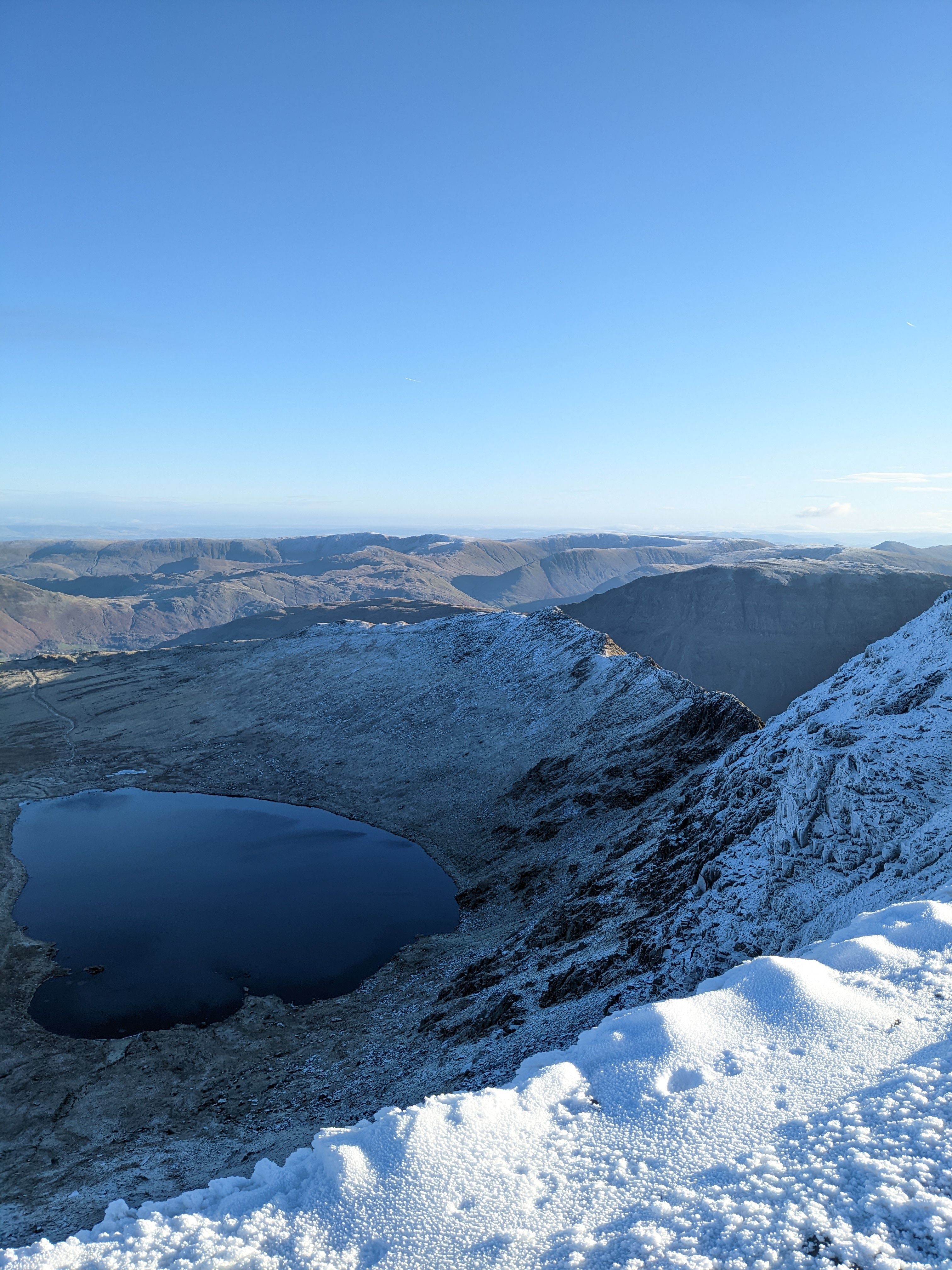 The long ridge of Skiddaw and Blencathra rising over farmland with snow on the tops