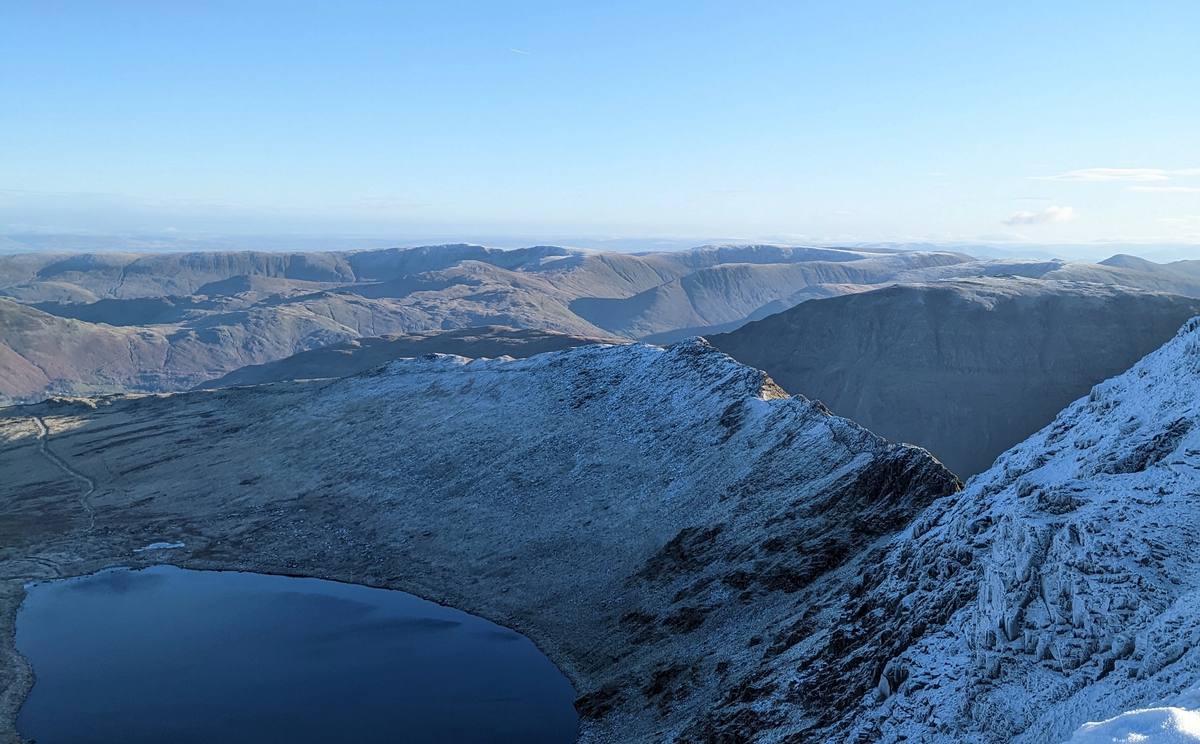 The long ridge of Skiddaw and Blencathra rising over farmland with snow on the tops