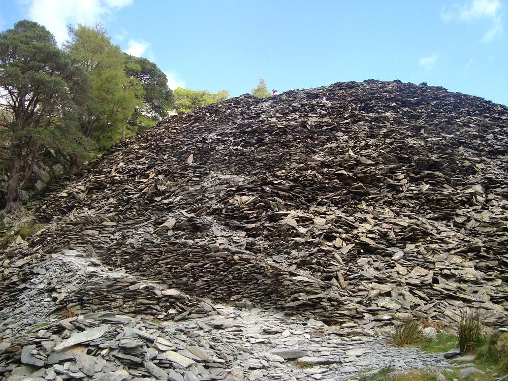 A steep slope of loose grey slate spoil below the summit of Castle Crag