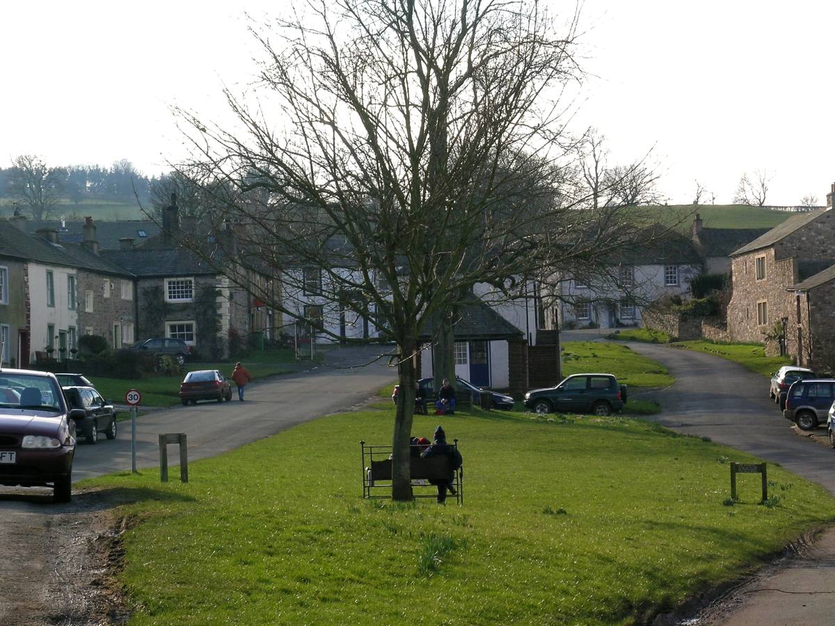 A wide village green with stone houses set back behind it