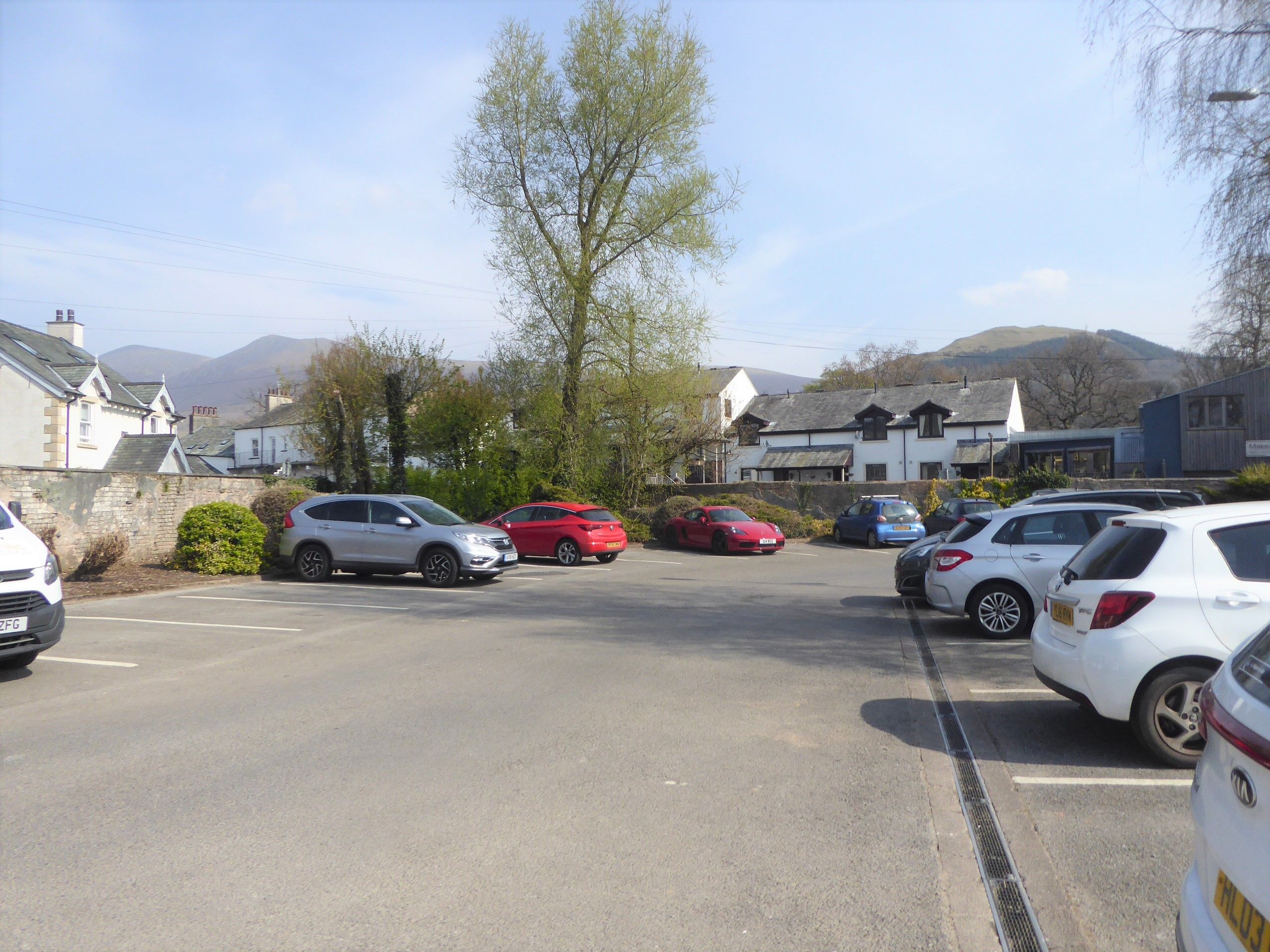 Cars parked at Otley Road car park in Keswick with the fells behind