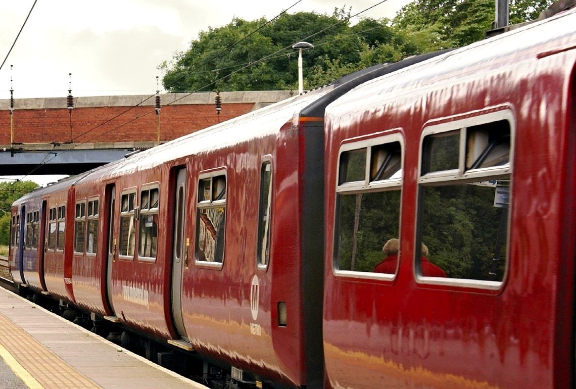 The side of a red train carriage standing at a station platform