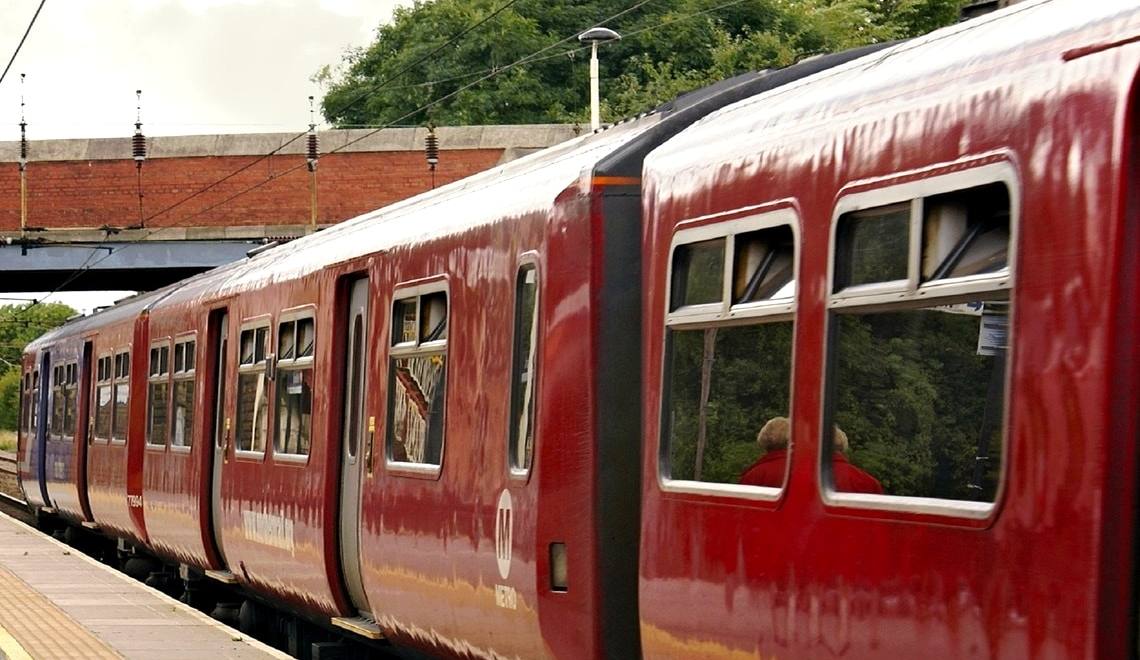 The side of a red train carriage standing at a station platform