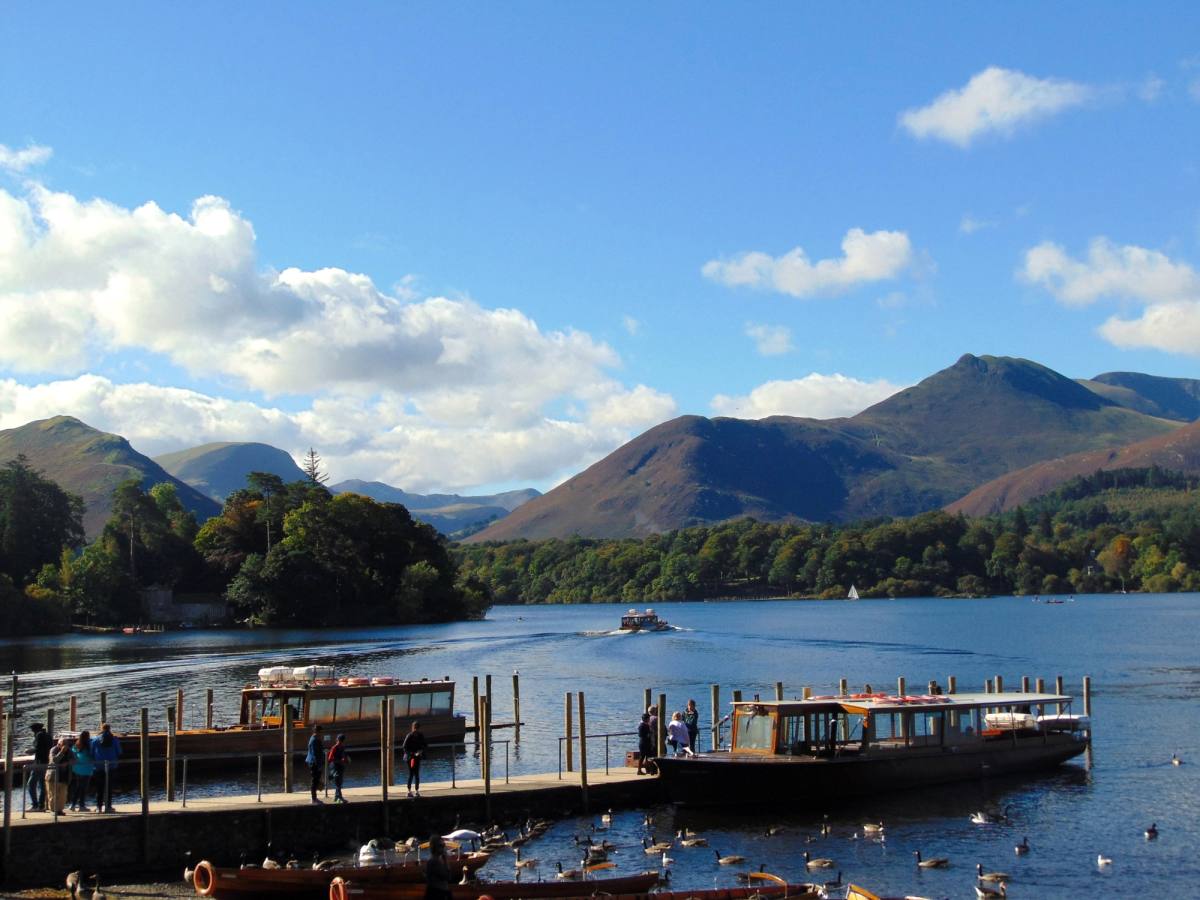 A wooden launch alongside the Derwentwater landing stages with Catbells beyond