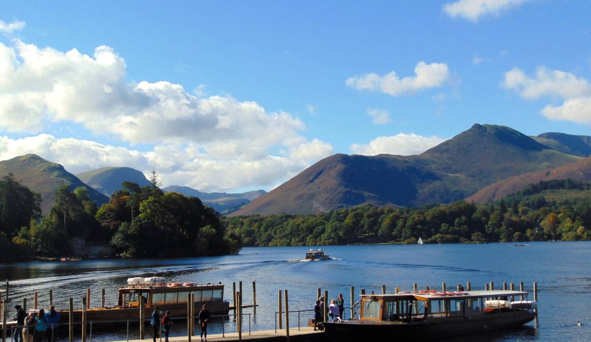 A wooden launch alongside the Derwentwater landing stages with Catbells beyond
