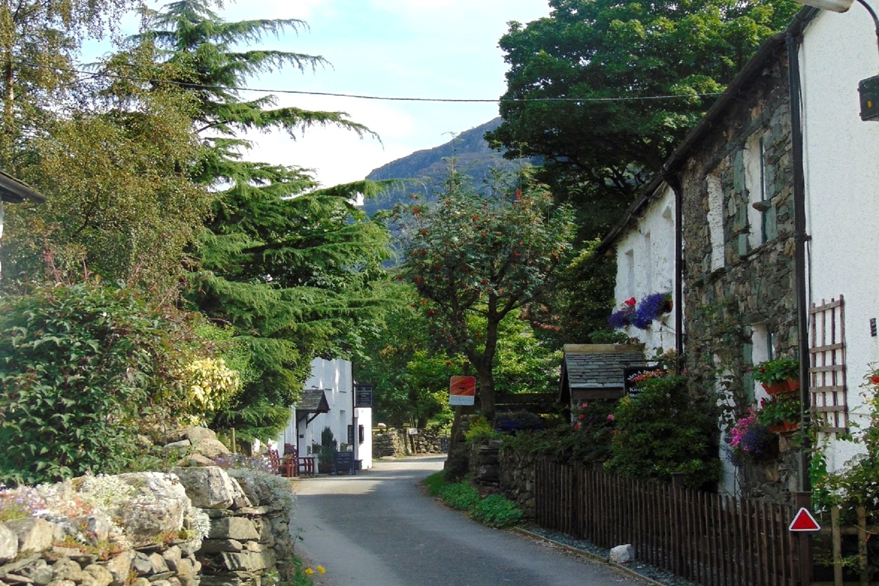 The narrow street through Seatoller between old cottages hung with flowers