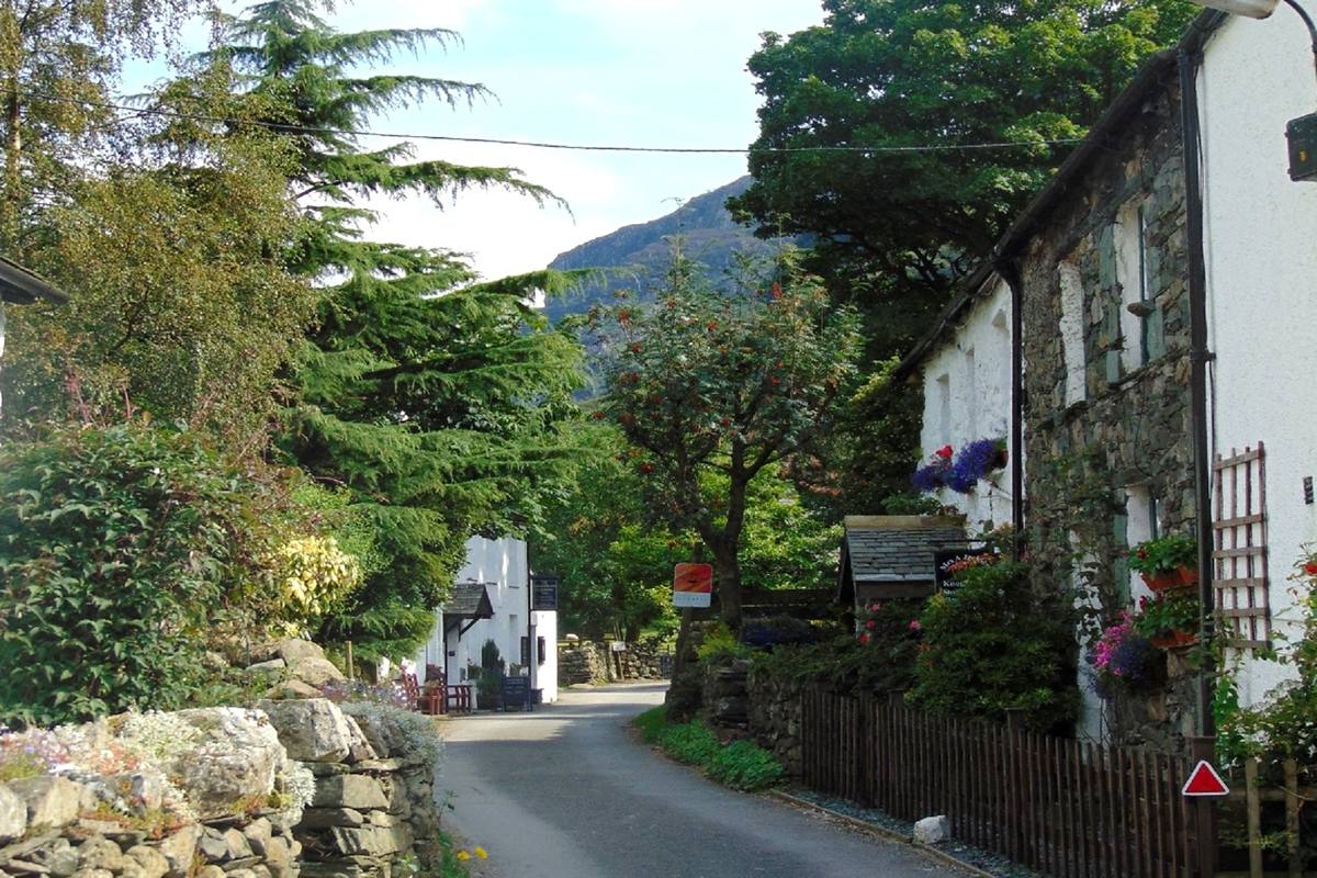 The narrow street through Seatoller between old cottages hung with flowers