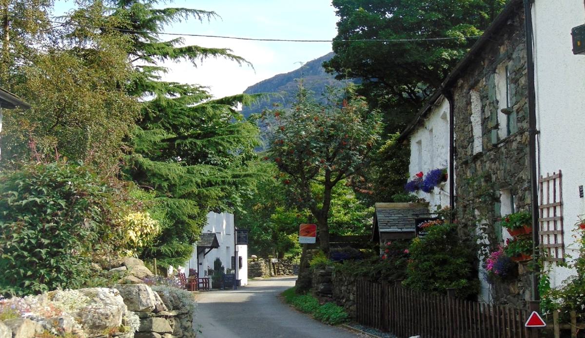 The narrow street through Seatoller between old cottages hung with flowers