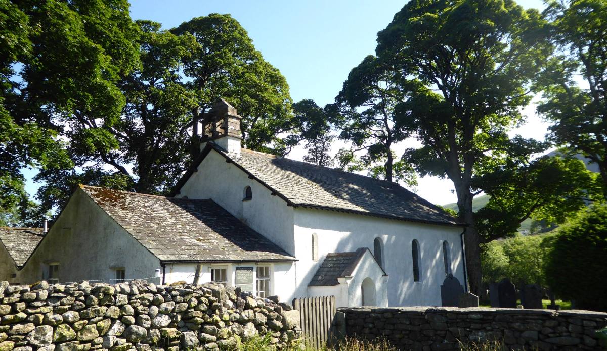 The small whitewashed Newlands church behind a drystone wall under a large tree