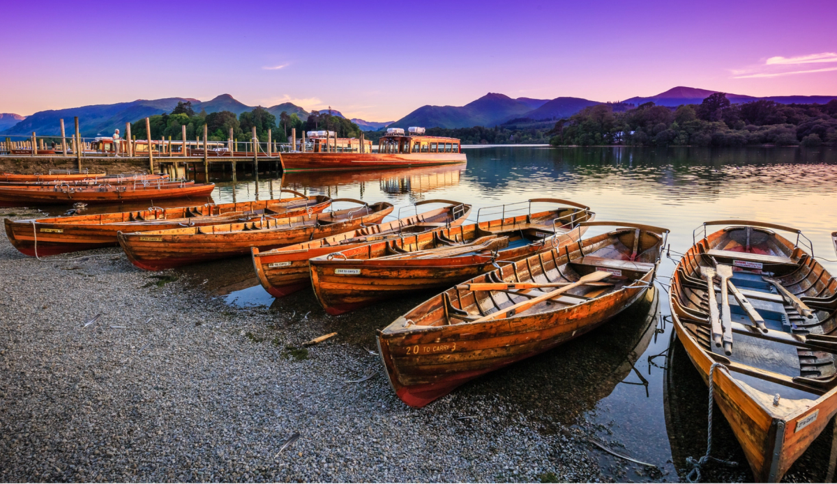 Wooden boats on the shores of Derwentwater with a sunrise sky