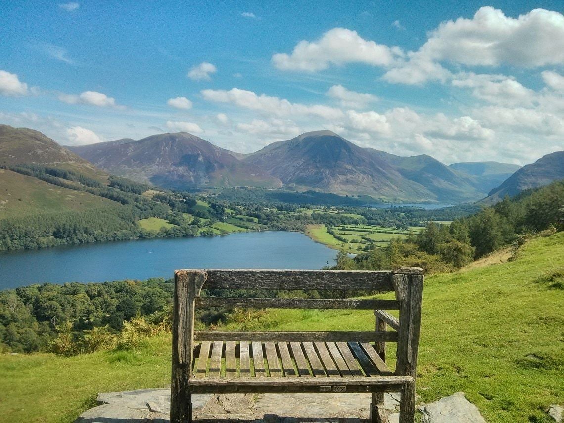 A weathered wooden bench on the fellside looking down over Crummock Water