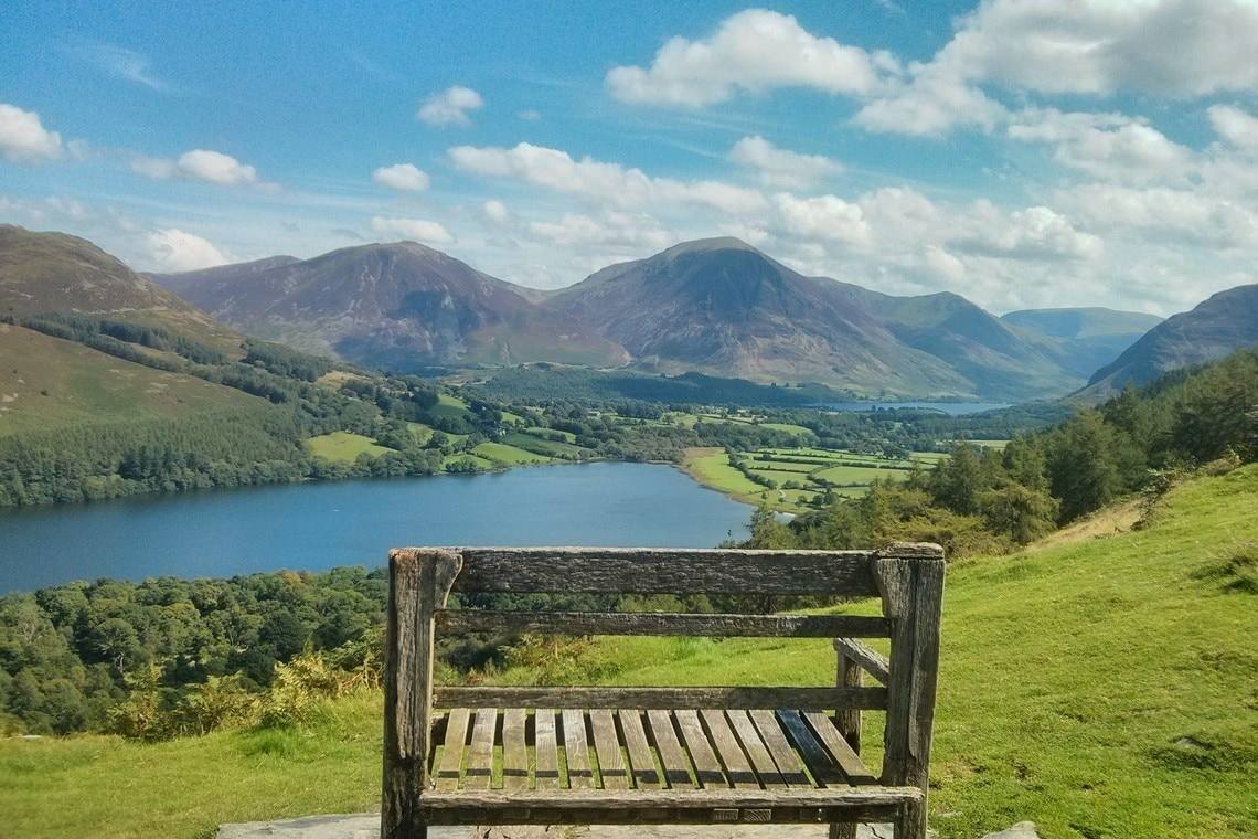 A weathered wooden bench on the fellside looking down over Crummock Water