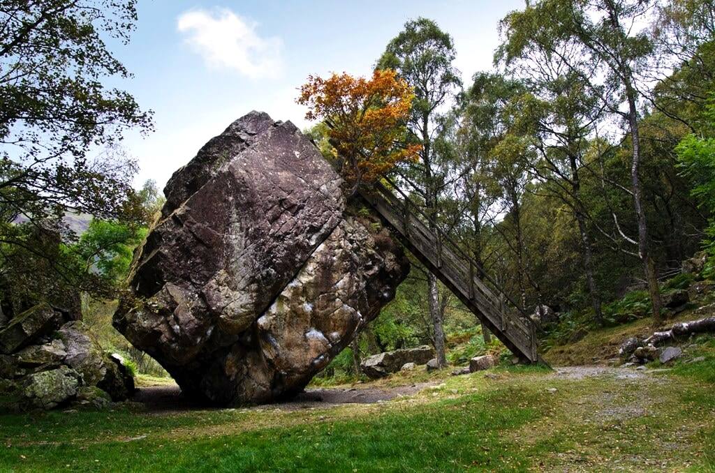 The Bowder Stone seen from the approach path with autumn trees behind